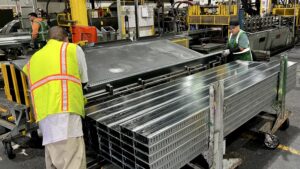 Workers handle freshly formed cold-formed steel (CFS) products as they exit one of CEMCO's roll-forming lines. The manufacturing process transforms the flat steel from slit coils into precisely shaped framing members used in commercial, institutional and residential construction.