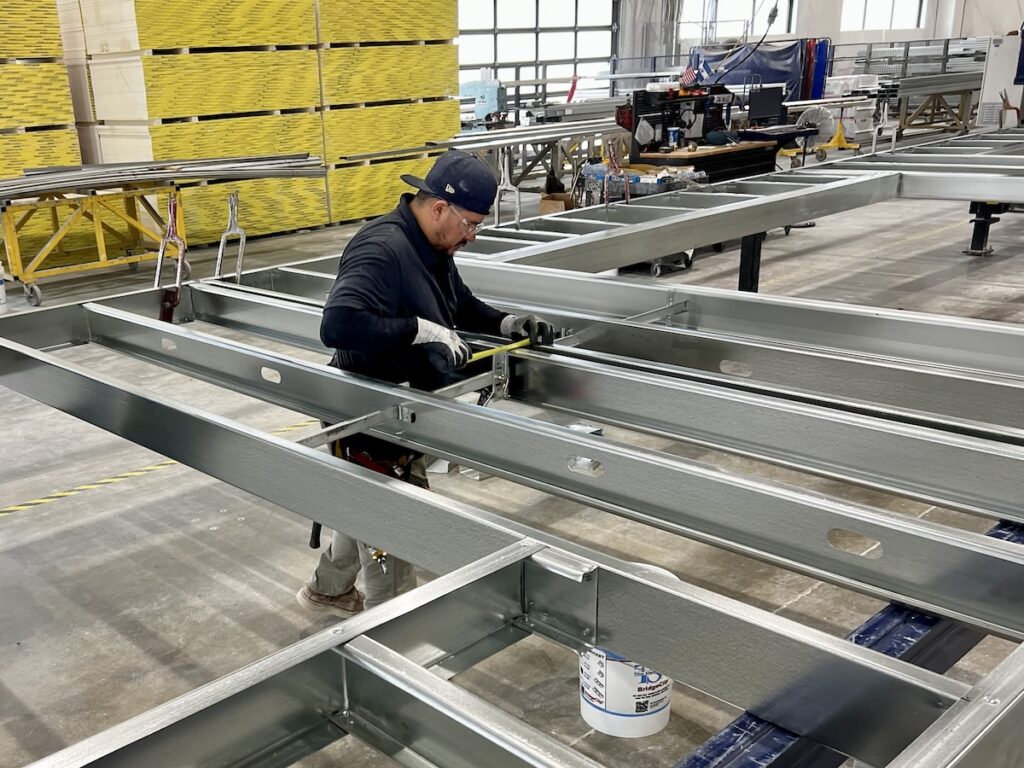 South Valley Prefab's Carlos Mendez assembles cold-formed steel (CFS) beneath “Melvin,” a giant CNC machine. Photo courtesy of Mark L. Johnson.
