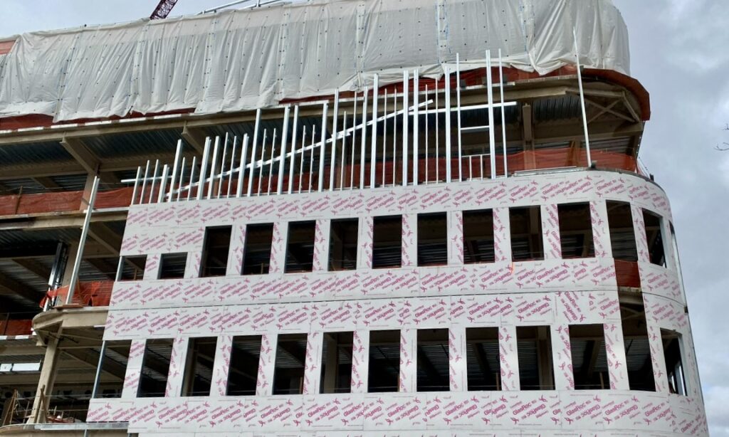 Cold-formed steel (CFS) framing fly-by assemblies at the south elevation are shown before capping top track installation. T.J. McCartney crews field-cut extended jamb studs to achieve the required slope.