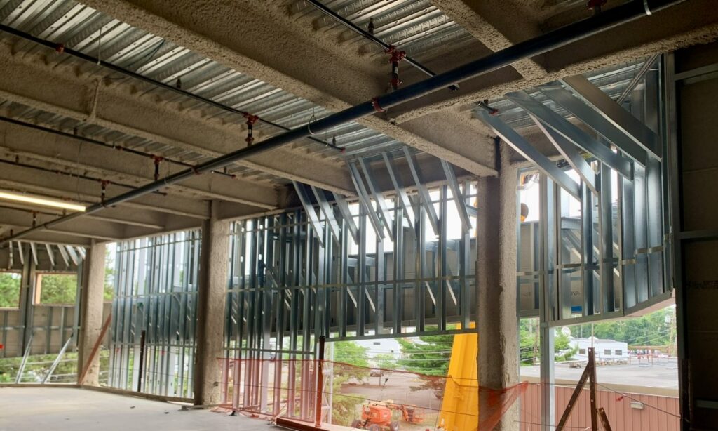 A secondary cold-formed steel (CFS) stud wall braces the exterior fly-by stud wall from Level 3 and above.