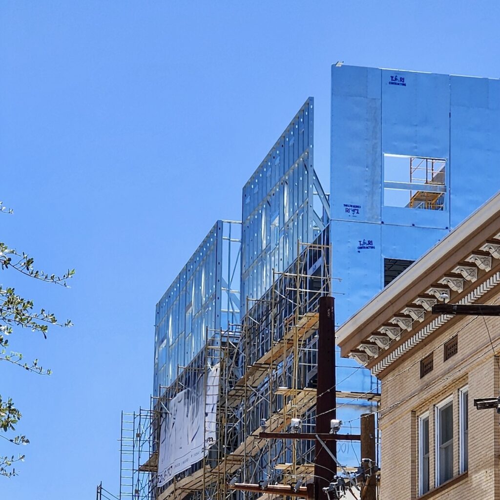 Prefabricated cold-formed steel (CFS) wall panels stand in place near a top floor, part of a system of vertically aligned bearing walls that run down to the foundation.