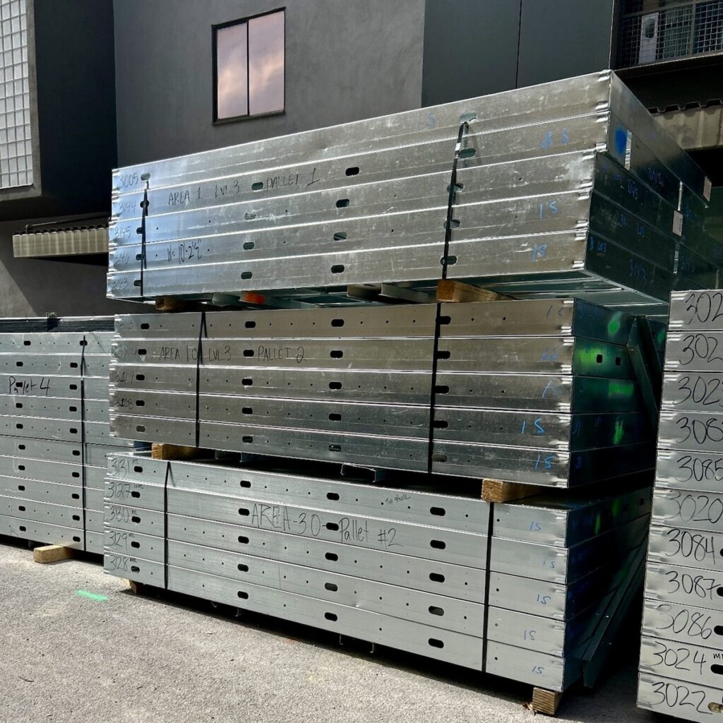 Stacks of prefabricated wall panels arrive on site, ready to be lifted into place.