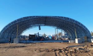 Steelo achieved a 30-meter clear span with a catenary arch system, using lightweight steel members to transfer loads through axial forces instead of bending.