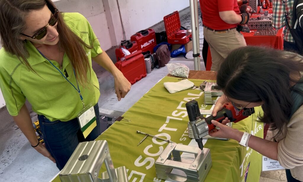 Cydney Skeens of Scottsdale Construction Systems demonstrates pop-riveting tips to engineer Suyun Sun of Gregory P. Luth &amp; Associates during Tool Time at the 2026 CFSEI Expo in Long Beach, California. Skeens is host of the "Roll Forming with ScotCyd" video series.