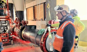 Large chiller pipes and valves are pre-assembled and sealed in staging area before being lifted into place