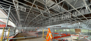 Construction images show the dual-curved lobby ceiling taking shape from coordinated CFS framing. Point-cloud data helped define stud and track locations across the compound geometry.
