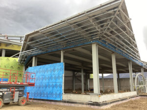The stepped roof geometry and extensive overhangs drove the design of the tall cold-formed steel (CFS) wall system and supporting framing.