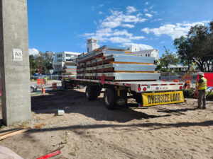 Prefabricated cold-formed steel wall panels arrive on site for installation. The panelized approach supported the project's accelerated schedule and limited staging space.